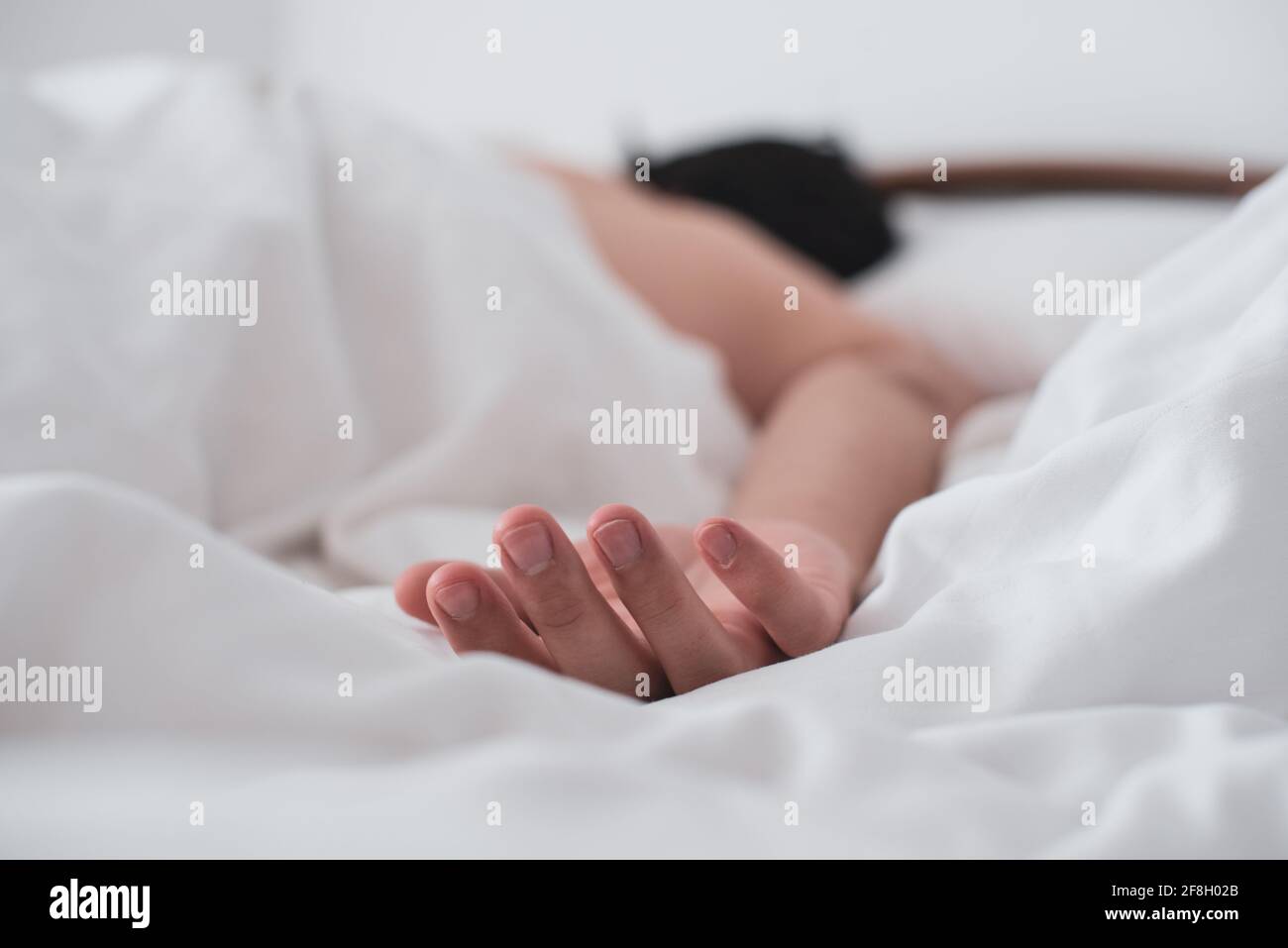 Primo piano della mano di un uomo capovolto sul letto mentre dorme. Foto Stock
