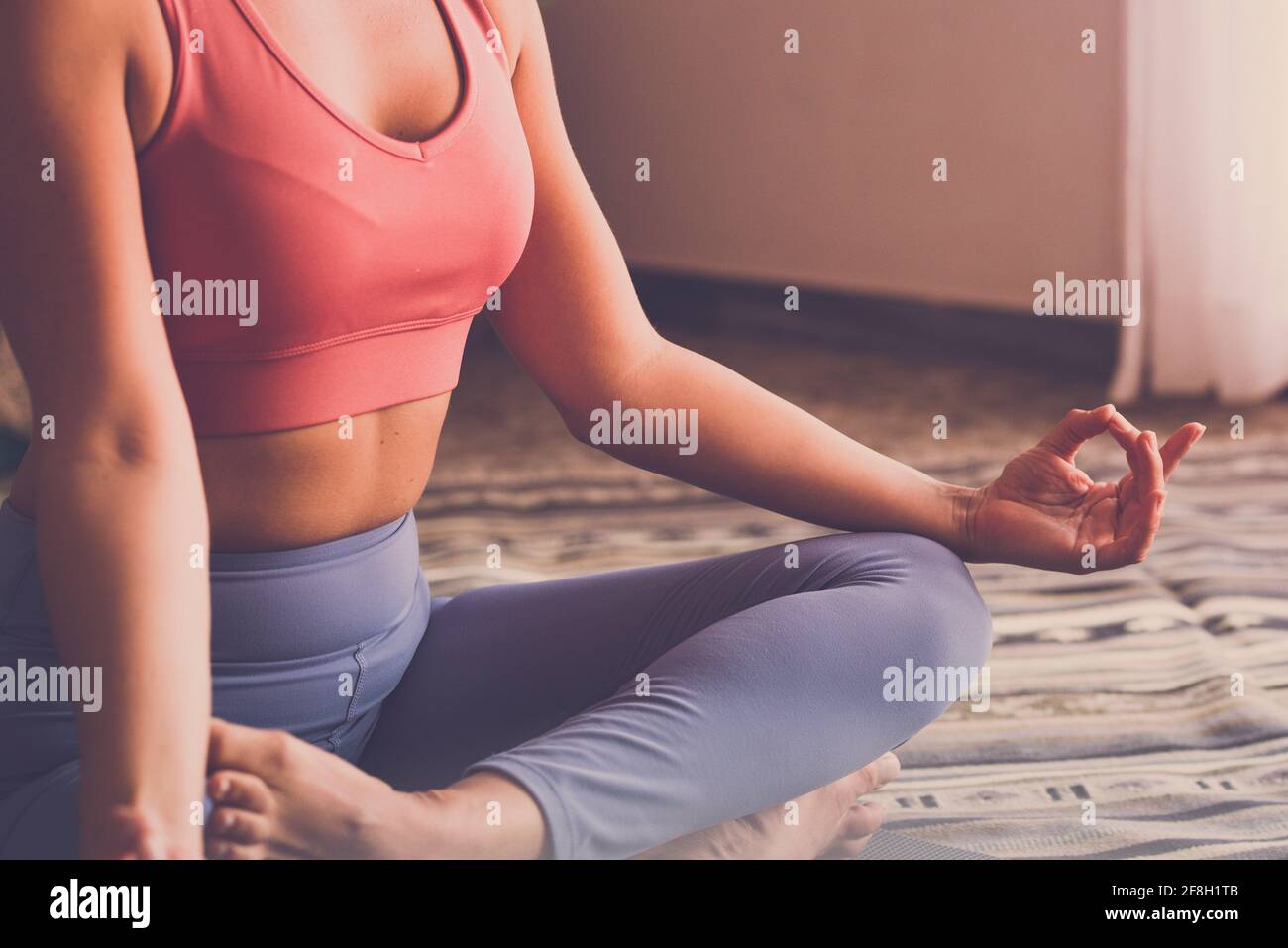 Primo piano concetto di corpo sano e anima. Vista ritagliata della donna americana sportiva medita sul tappetino yoga, facendo mudra gesto, seduta in lotus afte Foto Stock
