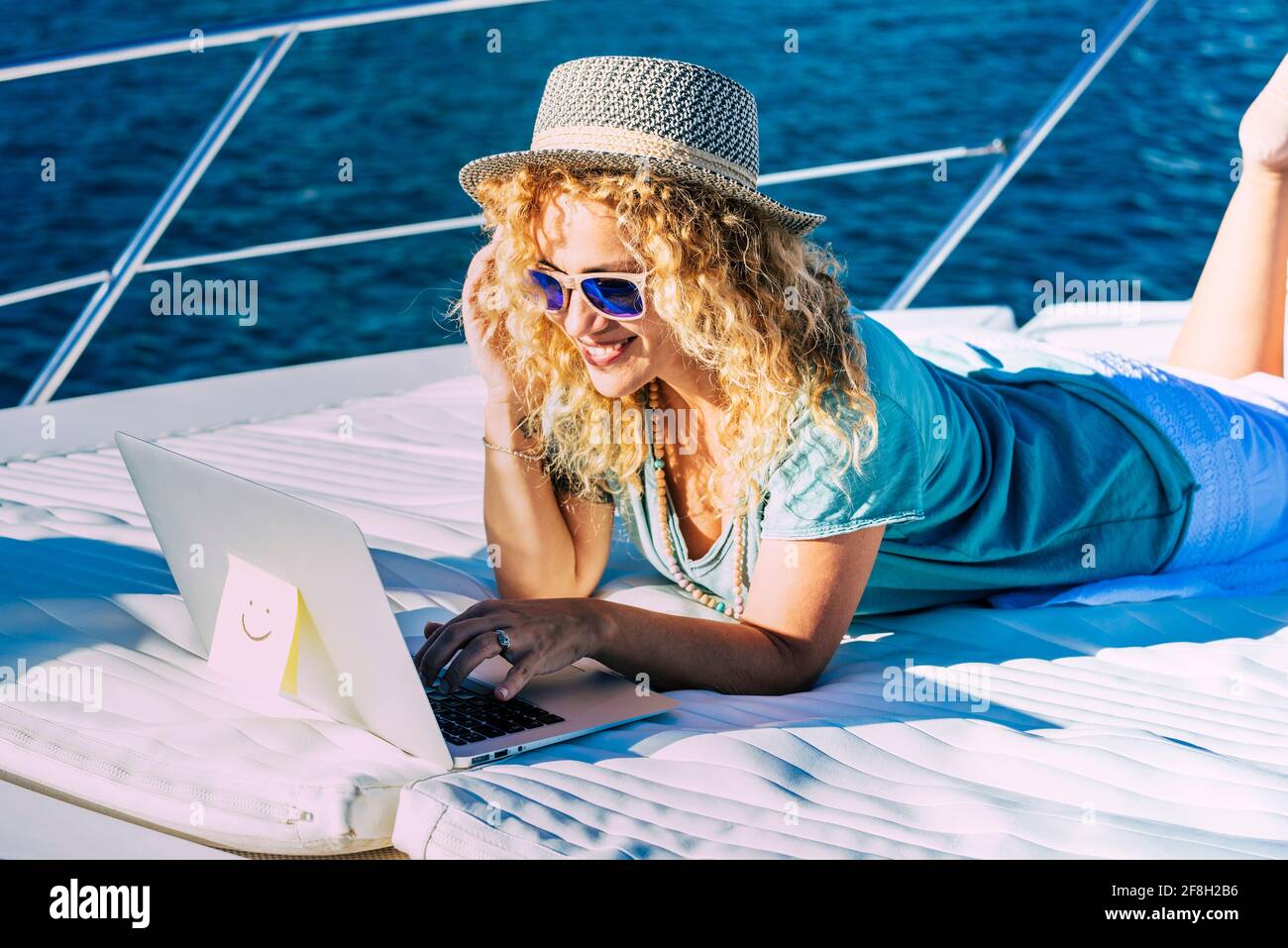 Donna allegra lavoro all'aperto con computer portatile sdraiarsi una barca che gode di libertà e connessione internet - concetto di persone e lavoro intelligente mod Foto Stock