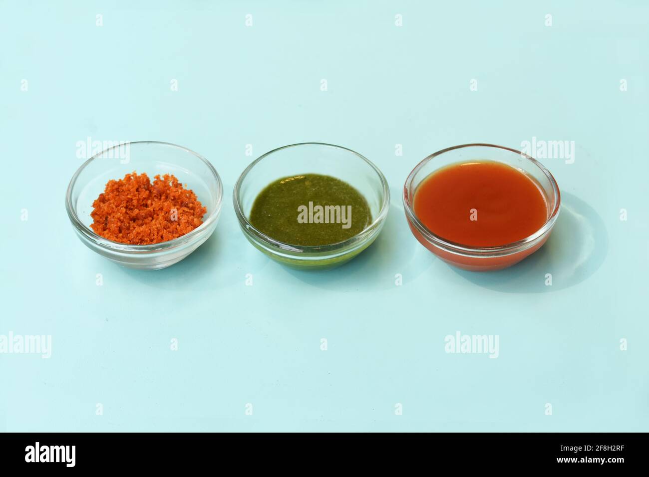 Set di tre chutney - salsa dolce, coriandolo-menta verde e arachide arachidi aglio chutney secco, su sfondo blu, vista dall'alto chiusa Foto Stock