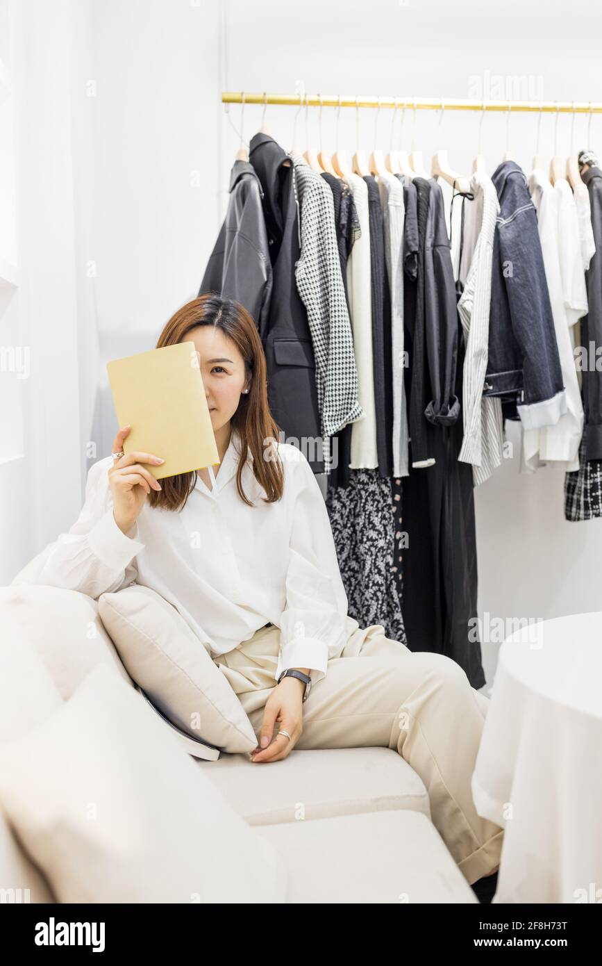 Startup piccola impresa, giovane donna cinese imprenditore utilizzando pianificatore settimanale in negozio Foto Stock