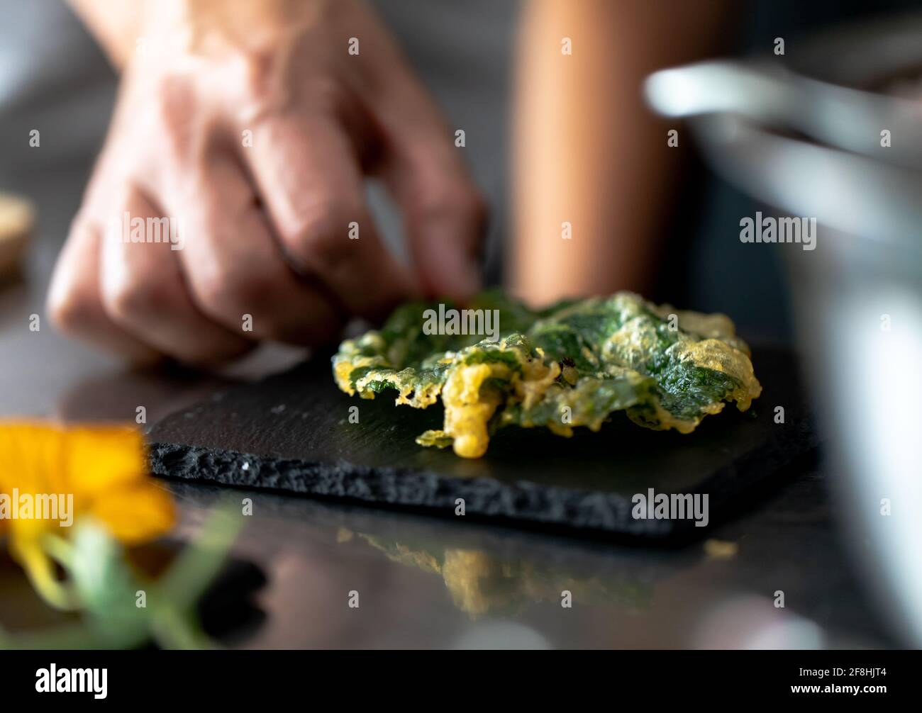 mano dell'uomo che prepara il cibo fritto su un'ardesia con la schiena leggero Foto Stock