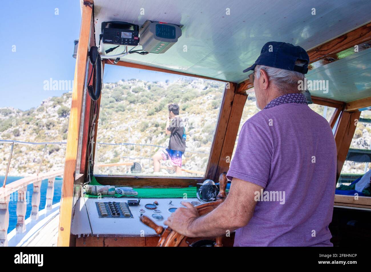 Il capitano della barca controlla la nave. Volante e quadro di comando yacht. Pronto a viaggiare in mare. Coperta in legno all'interno della barca a vela. Nave sul molo. Buona tesseramento Foto Stock