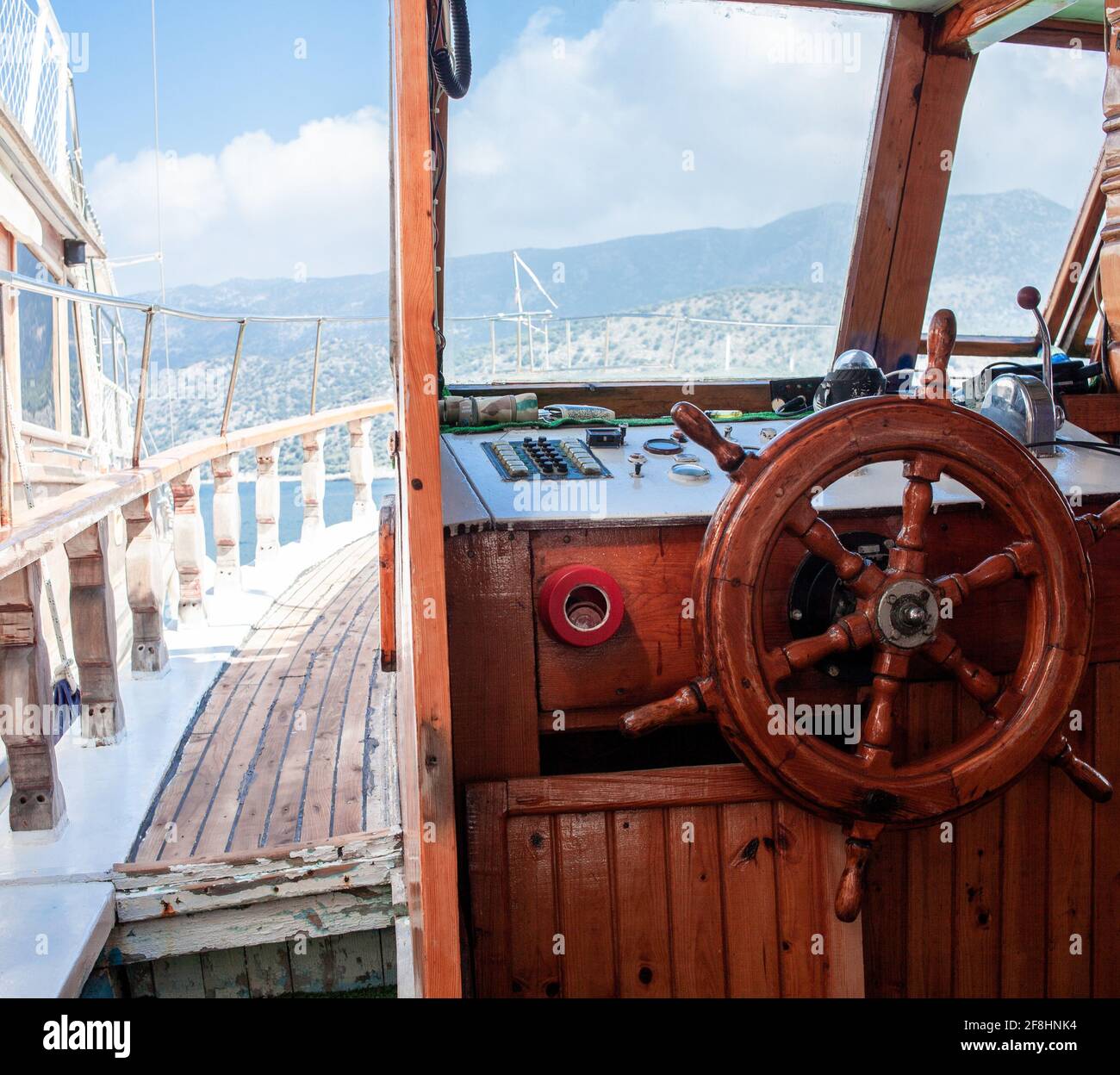 Volante e quadro di comando yacht. Pronto a viaggiare in mare. Coperta in legno all'interno della barca a vela. Nave sul molo. Bel tempo per navigare. Demre, Turchia - Foto Stock