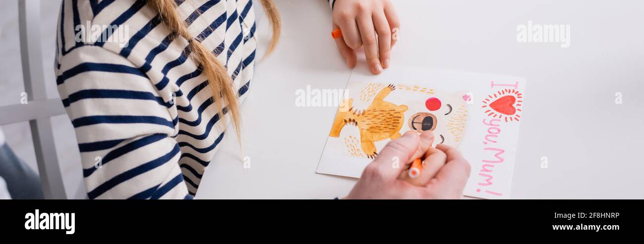 vista parziale del padre e della figlia che disegnano la scheda di giorno delle madri con i love voi la mamma che lettering, la bandiera Foto Stock