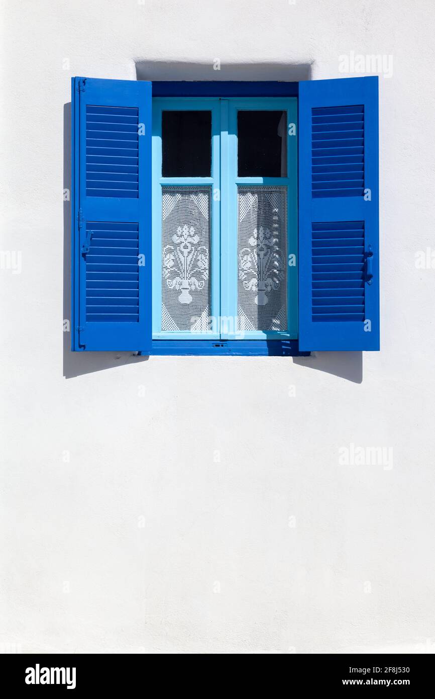 Tipica architettura locale delle isole Cicladi, Grecia, pareti bianche e finestre blu, occasionalmente con ricami come tende. Foto Stock