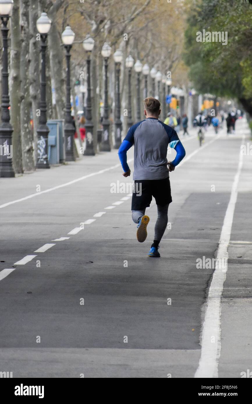 Vista posteriore di un giovane che corre lungo il viale. Foto Stock