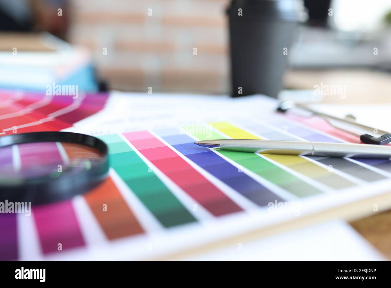 La tavolozza dei colori con penna e lente di ingrandimento è sul tavolo Foto Stock