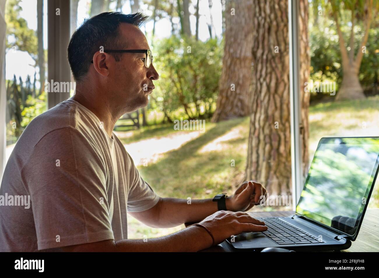Un uomo che lavora a casa, utilizzando un computer portatile. Foto Stock