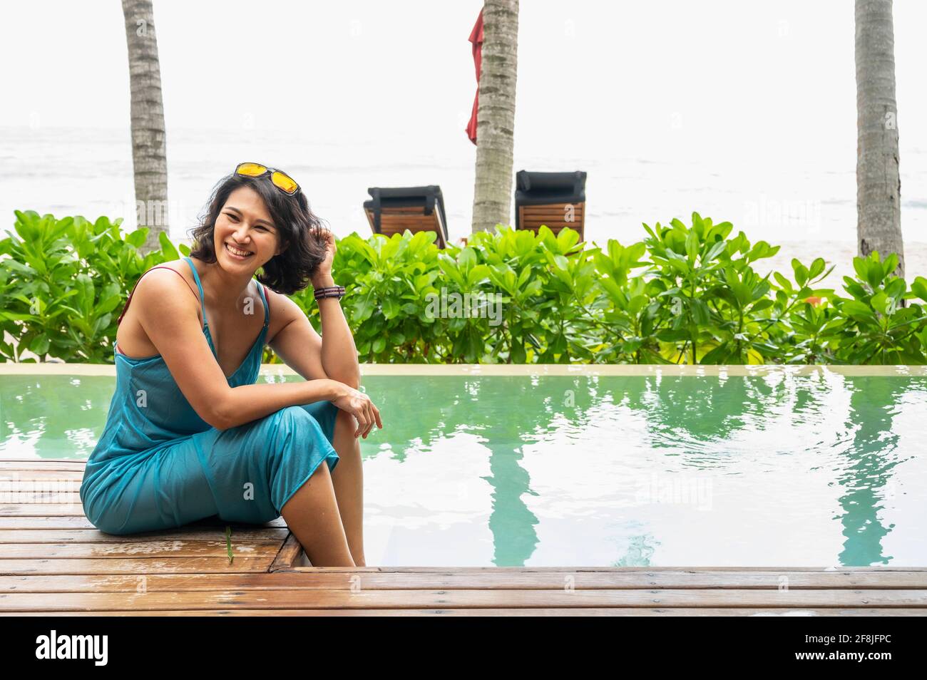donna seduta vicino alla piscina sull'isola tropicale di Koh Phangan Foto Stock