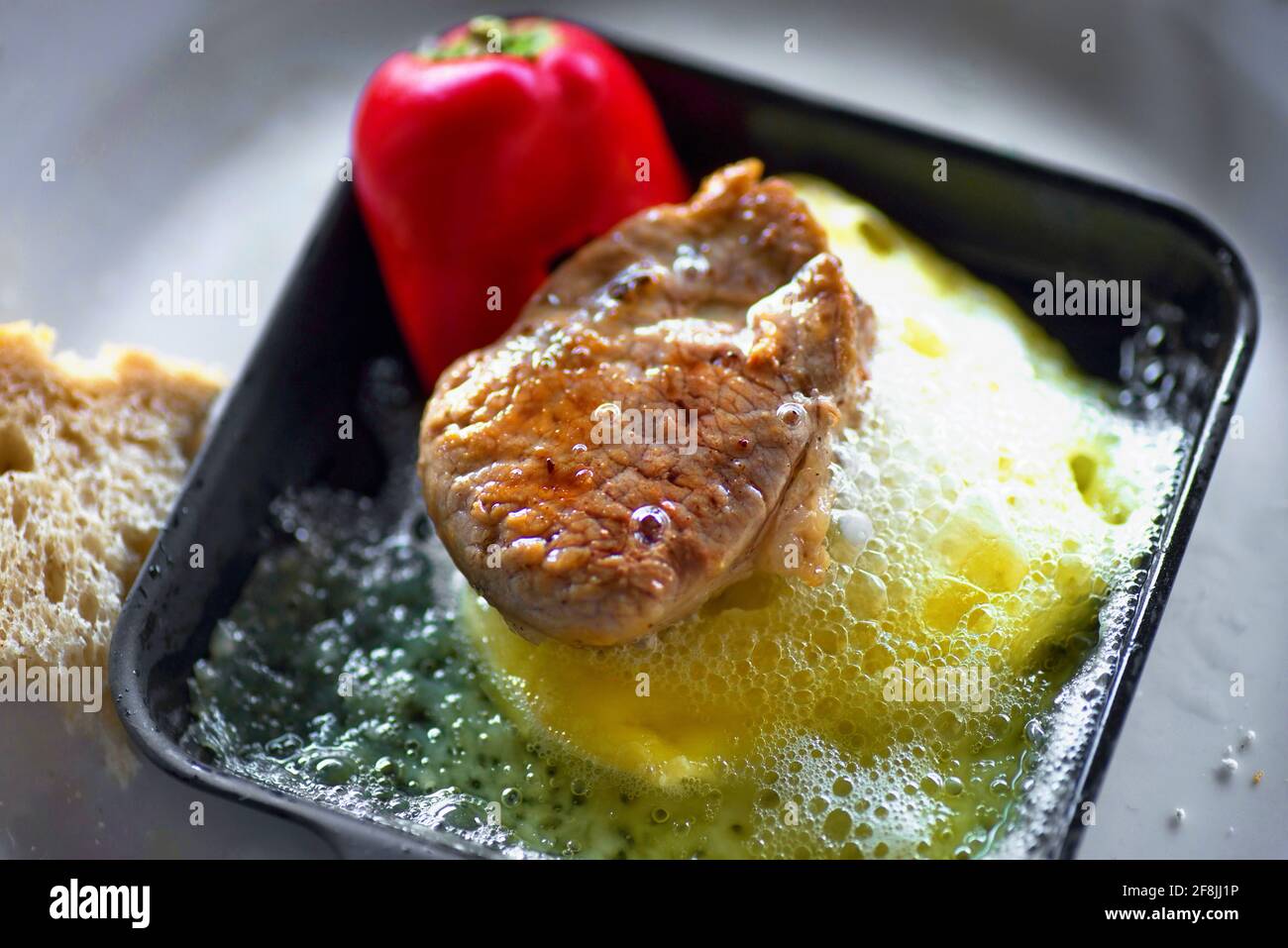 Piccola bistecca di manzo frittura su formaggio caldo e pepe rosso su griglia di padella di raclette, primo piano. Foto Stock