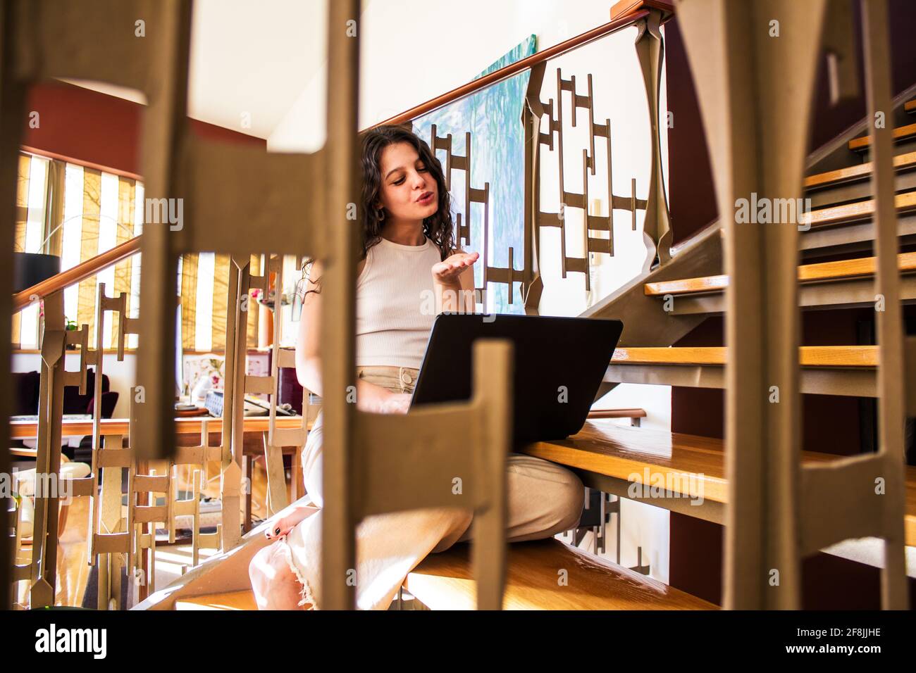 giovane donna che parla con il computer portatile seduto sulle scale a. casa Foto Stock