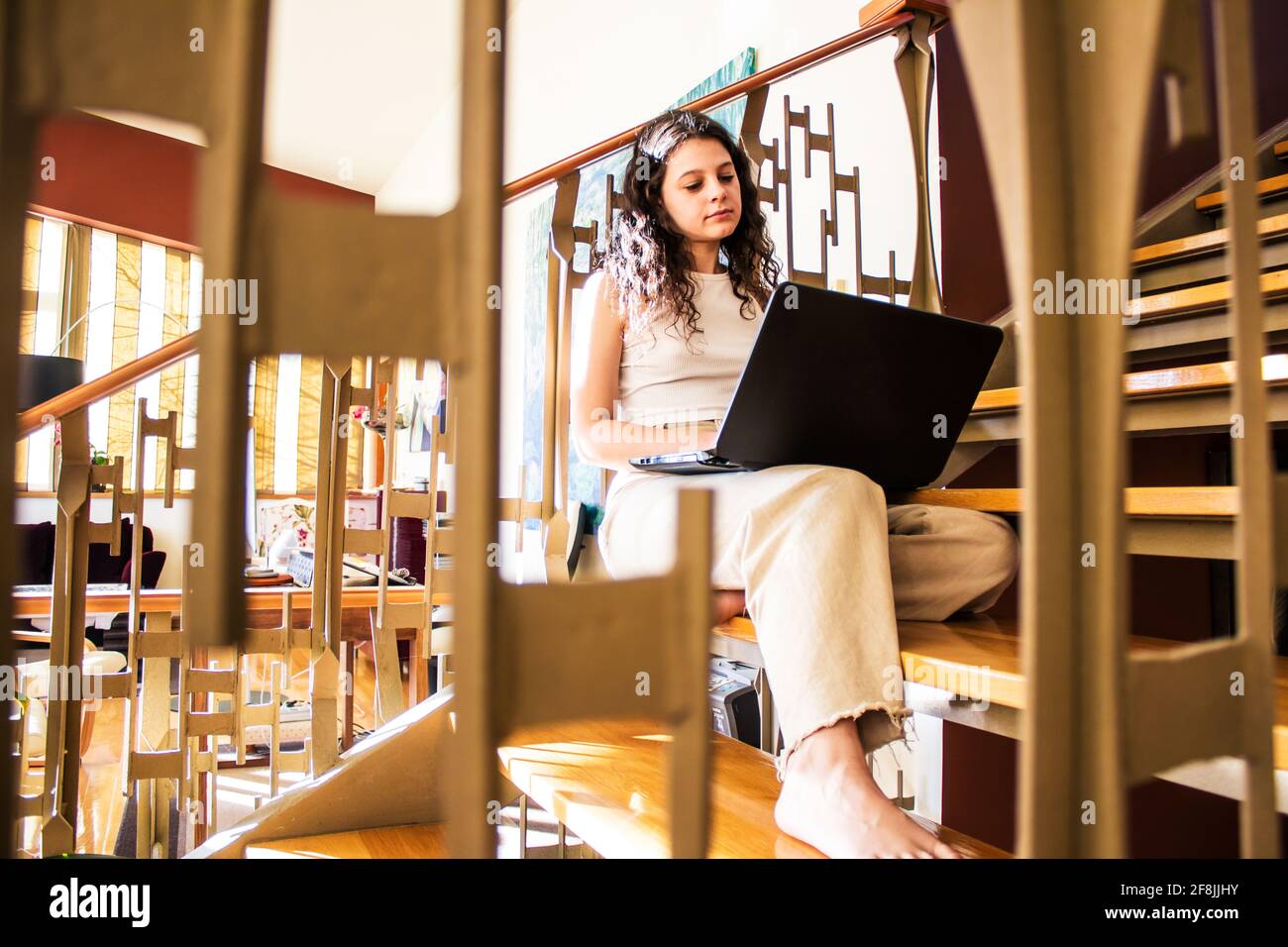 giovane donna che parla con il computer portatile seduto sulle scale a. casa Foto Stock