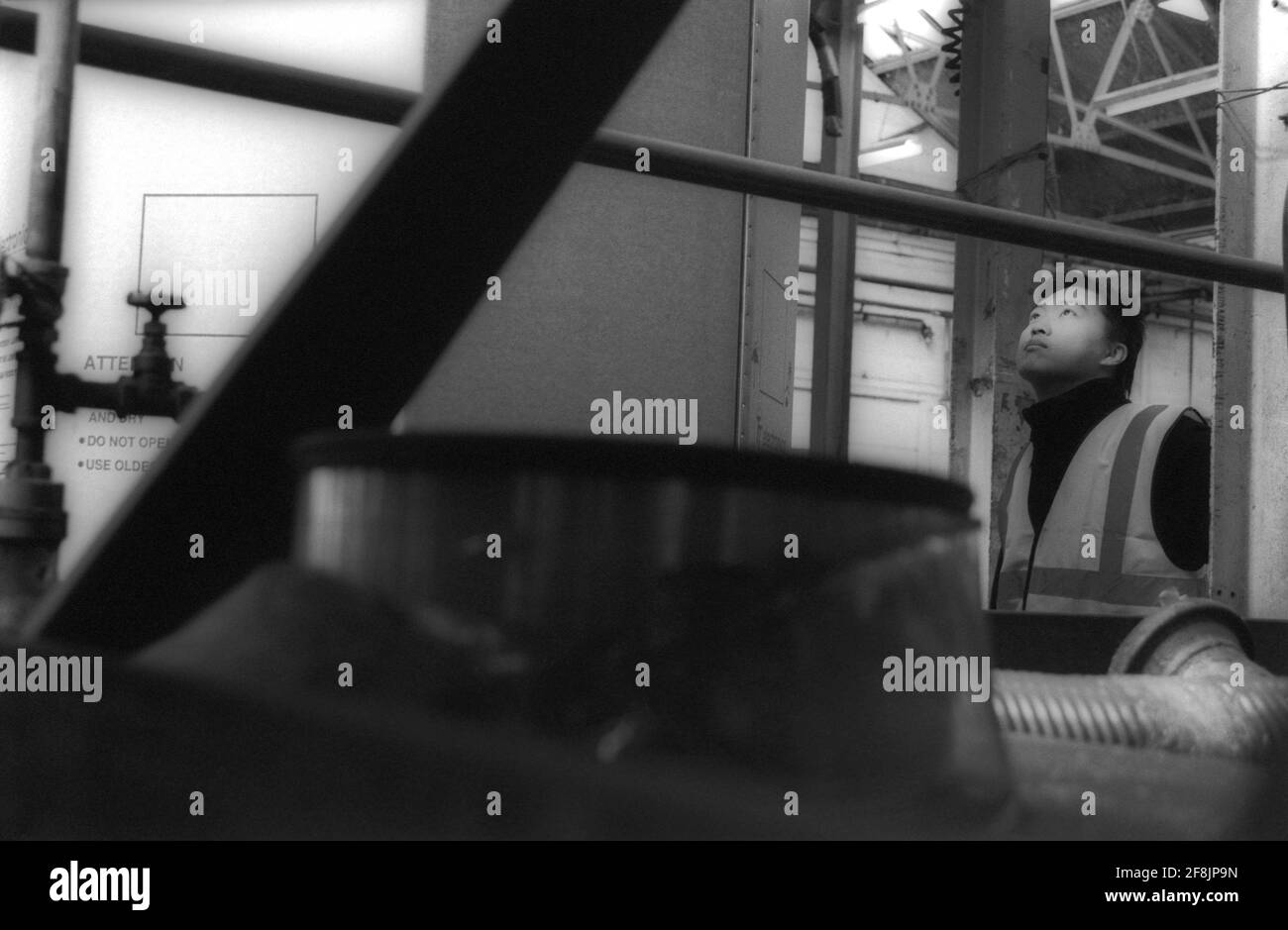 Lavoratore maschile in fabbrica che controlla i contenitori di stoccaggio Foto Stock