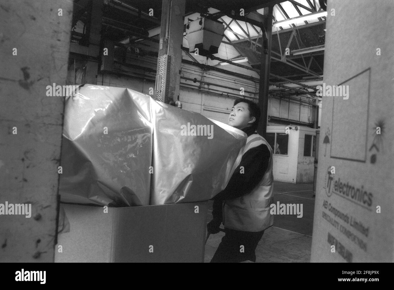 Lavoratore maschile in fabbrica che controlla i contenitori di stoccaggio Foto Stock