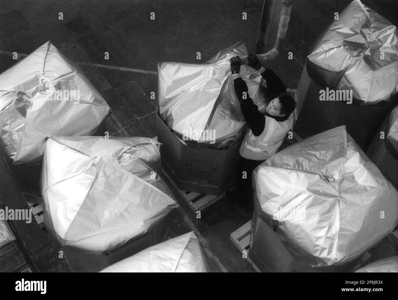 Lavoratore maschile in fabbrica che controlla i contenitori di stoccaggio Foto Stock