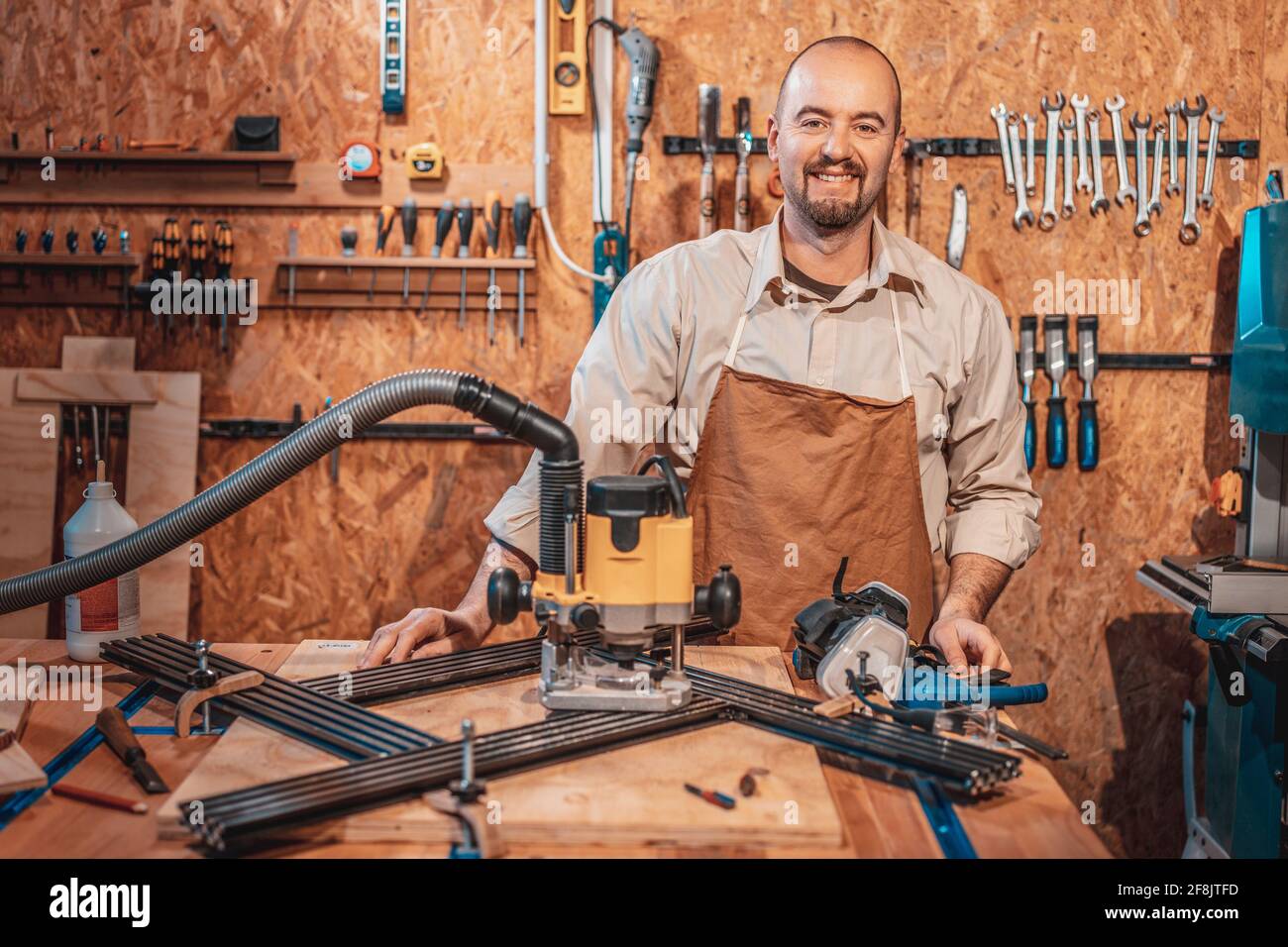 ritratto di un carpentiere caucasico sorridente con grembiule nel suo officina Foto Stock