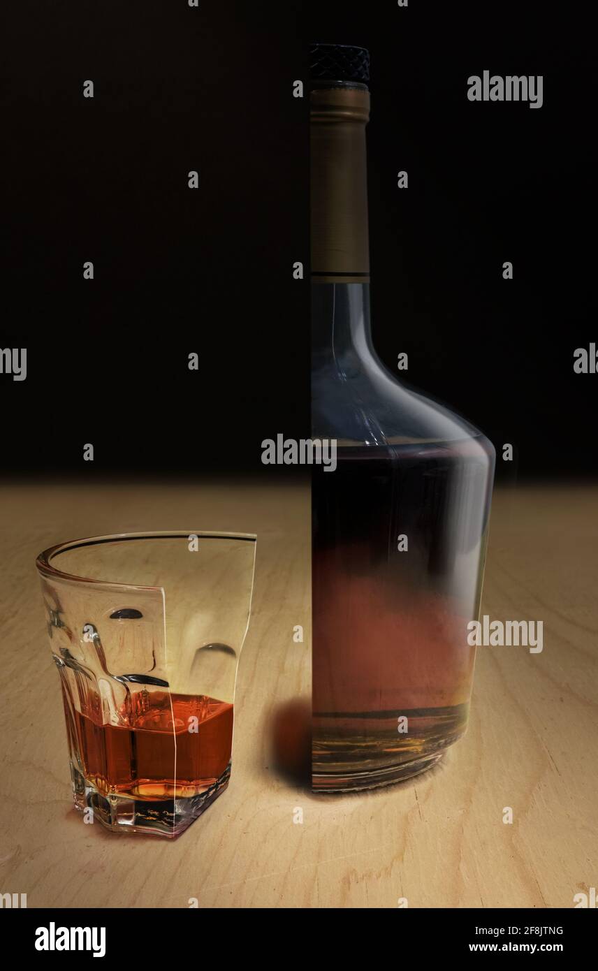 Su una superficie di legno, un bicchiere di liquore duro e la bottiglia, entrambi tagliati a metà. Foto Stock