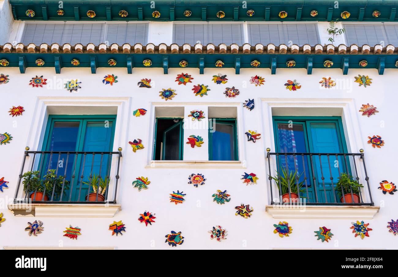 Facciata bianca di un vecchio ostello nel quartiere Realejo Di Granada (Spagna) decorata con molti soli in ceramica Foto Stock