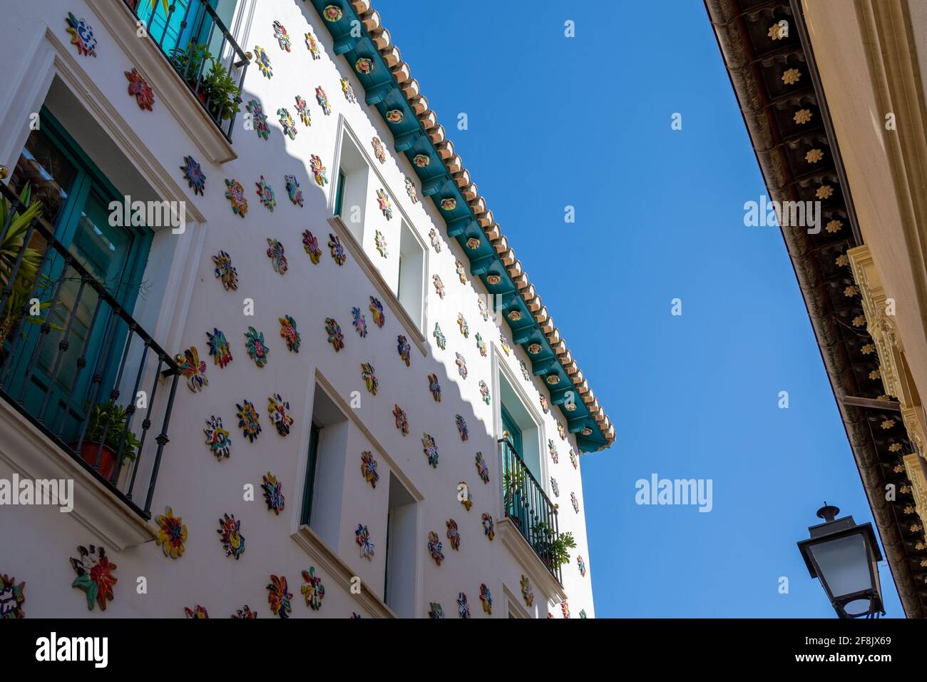 Facciata bianca di un vecchio ostello nel quartiere Realejo Di Granada (Spagna) decorata con molti soli in ceramica Foto Stock