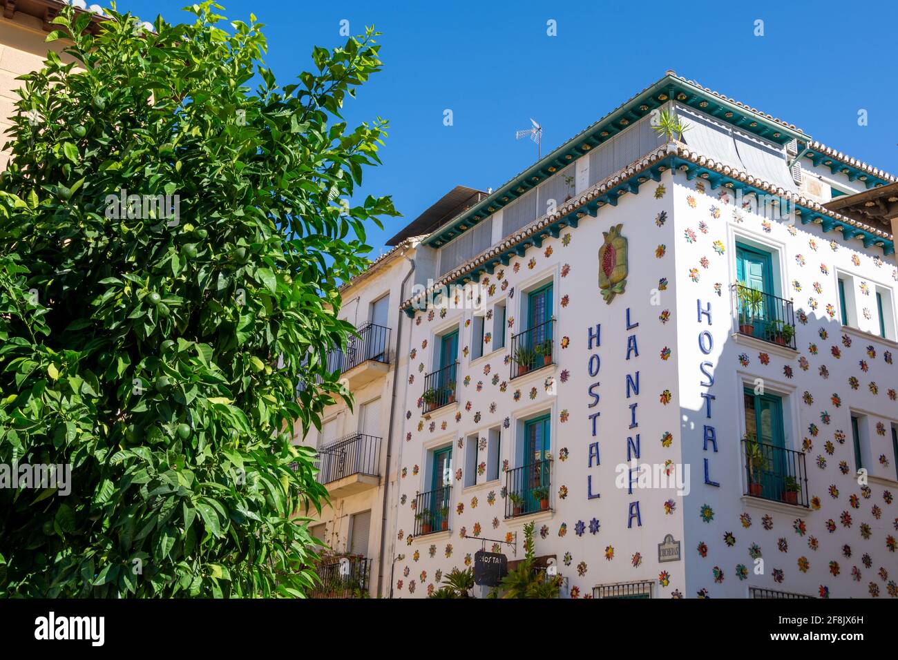 Facciata bianca di un vecchio ostello nel quartiere Realejo Di Granada (Spagna) decorata con molti soli in ceramica Foto Stock
