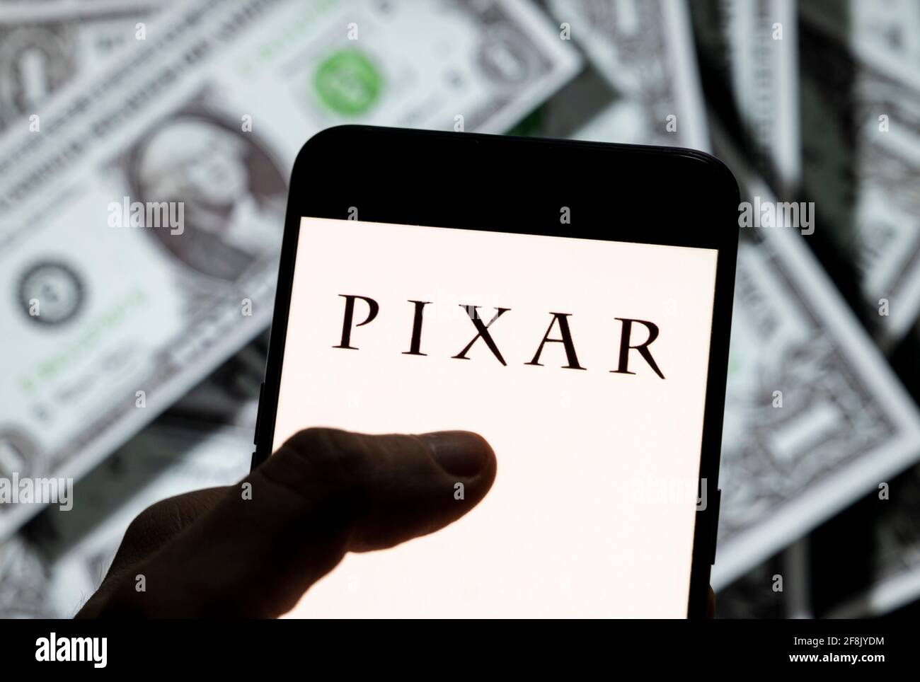 In questa illustrazione fotografica, lo studio cinematografico americano di animazione del computer di proprietà di Disney, il logo Pixar è visto sullo schermo di un dispositivo mobile Android con la valuta dell'icona del dollaro degli Stati Uniti, simbolo dell'icona di dollari sullo sfondo. Foto Stock