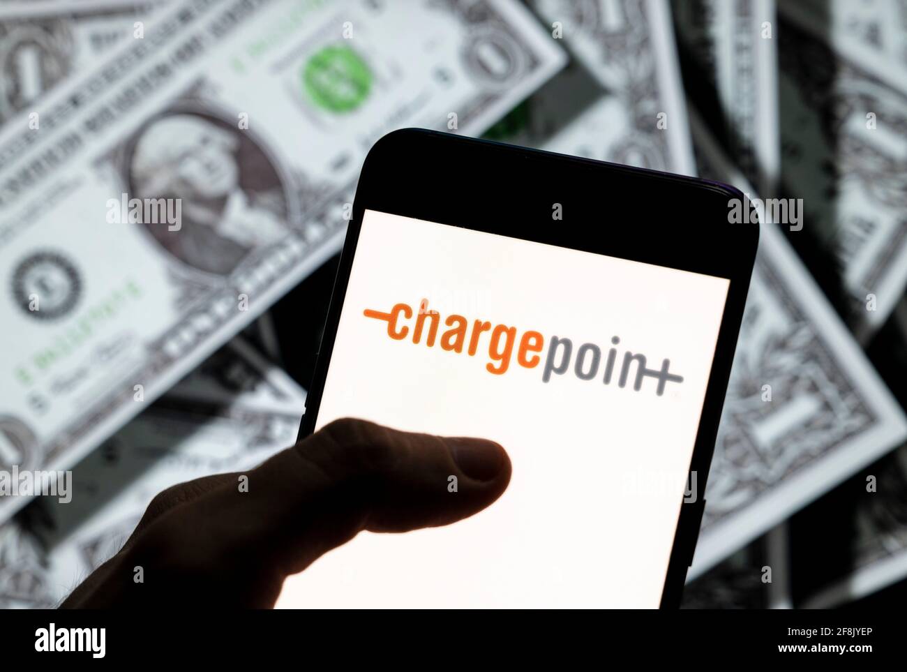 In questa illustrazione fotografica, il logo ChargePoint Holdings della società americana di infrastrutture per veicoli elettrici viene visualizzato sullo schermo di un dispositivo mobile Android con la valuta dell'icona del dollaro degli Stati Uniti e il simbolo dell'icona in dollari sullo sfondo. Foto Stock
