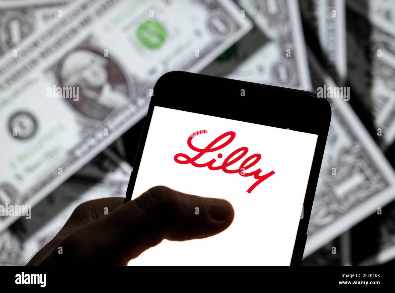 Cina. 14 Apr 2021. In questa illustrazione fotografica, il logo della società farmaceutica americana Lilly è visualizzato sullo schermo di un dispositivo mobile Android con la valuta dell'icona del dollaro statunitense, simbolo dell'icona in dollari sullo sfondo. (Foto di Budrul Chukrut/SOPA Images/Sipa USA) Credit: Sipa USA/Alamy Live News Foto Stock