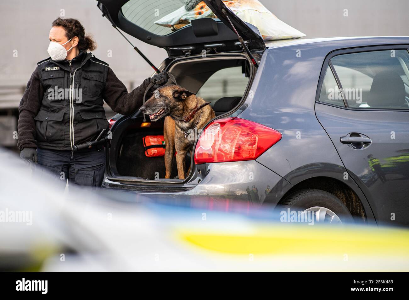 Bad Bentheim, Germania. 14 Apr 2021. Abby, un cane da pastore belga in servizio presso la polizia federale, cerca un scarpone per auto per la droga in un parcheggio sull'autostrada A 30 poco dopo il confine tedesco-olandese. La polizia federale, insieme ai colleghi della polizia di Stato della bassa Sassonia, sta effettuando un controllo su larga scala sull'autostrada A 30, vicino al confine tedesco-olandese. L'obiettivo dell'operazione di controllo su larga scala è la lotta alla criminalità transfrontaliera. Credit: Guido Kirchner/dpa/Alamy Live News Foto Stock