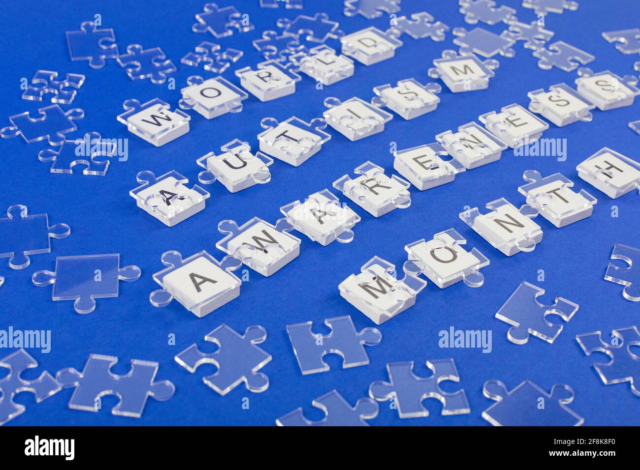 Background di consapevolezza dell'autismo mondiale. Puzzle trasparente dettagli puzzle su iscrizione su sfondo blu. Foto Stock