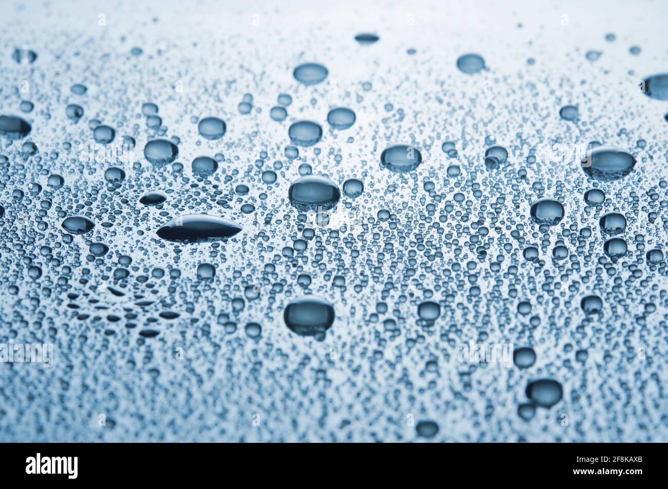 Primo piano goccia acqua su uno sfondo lucido. Immagine con tonalità blu. DOF poco profondo. Foto Stock