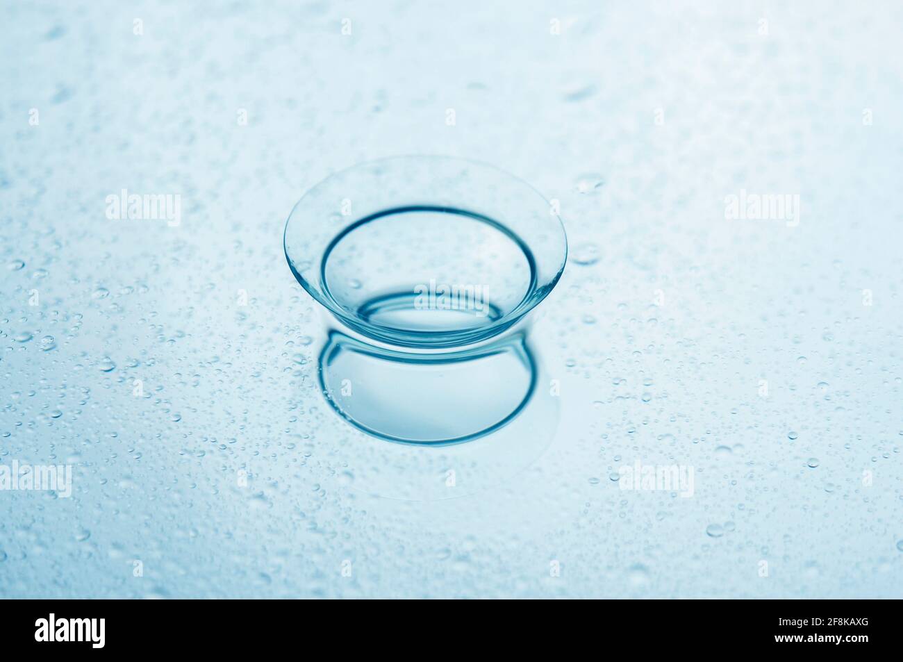 Lente a contatto con gocce d'acqua su uno sfondo a specchio. Primo piano. Foto Stock