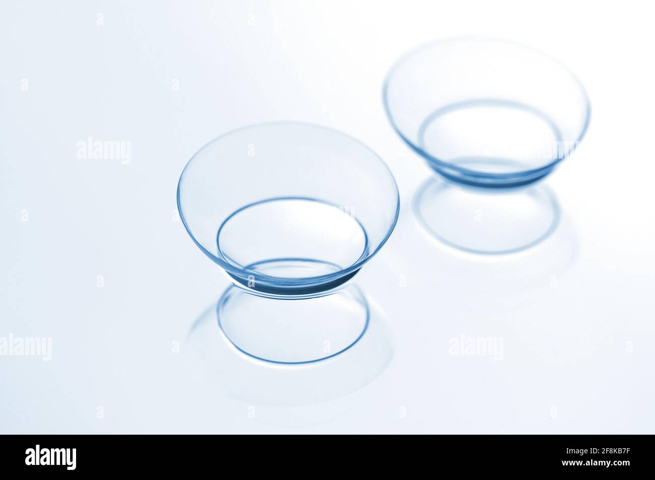 Due lenti a contatto con riflessi su sfondo blu. Foto Stock