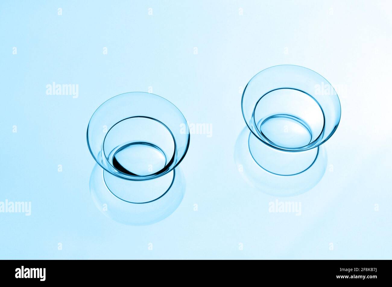 Due lenti a contatto con riflessi su sfondo blu. Foto Stock