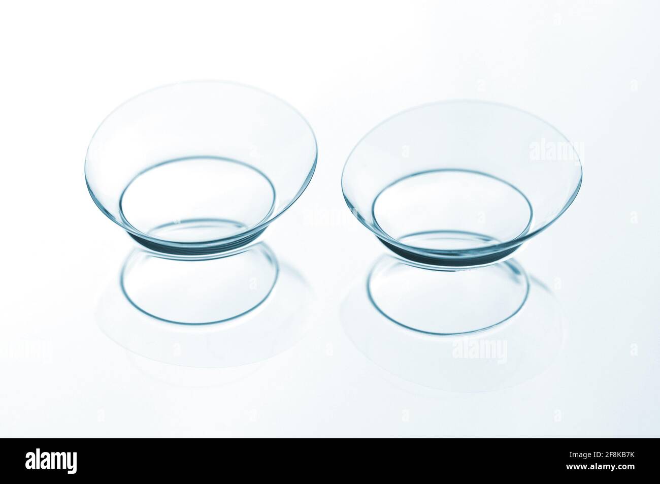 Due lenti a contatto con riflessi su sfondo blu. Foto Stock