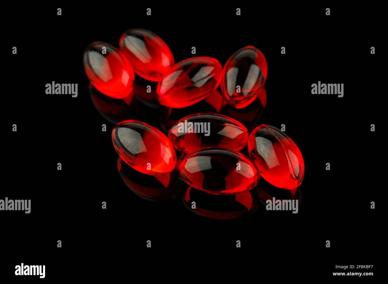 Pillole di vitamina rossa su sfondo nero. Messa a fuoco selettiva limitata alle pillole frontali. Foto Stock