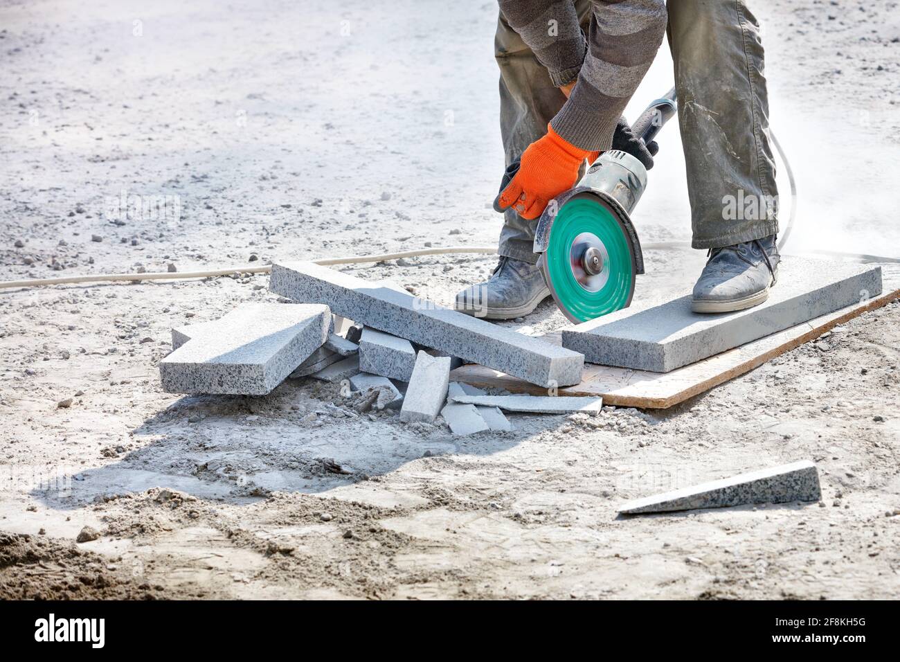 Il costruttore utilizza una smerigliatrice e un disco da taglio diamantato per tagliare i blocchi di granito. Foto Stock