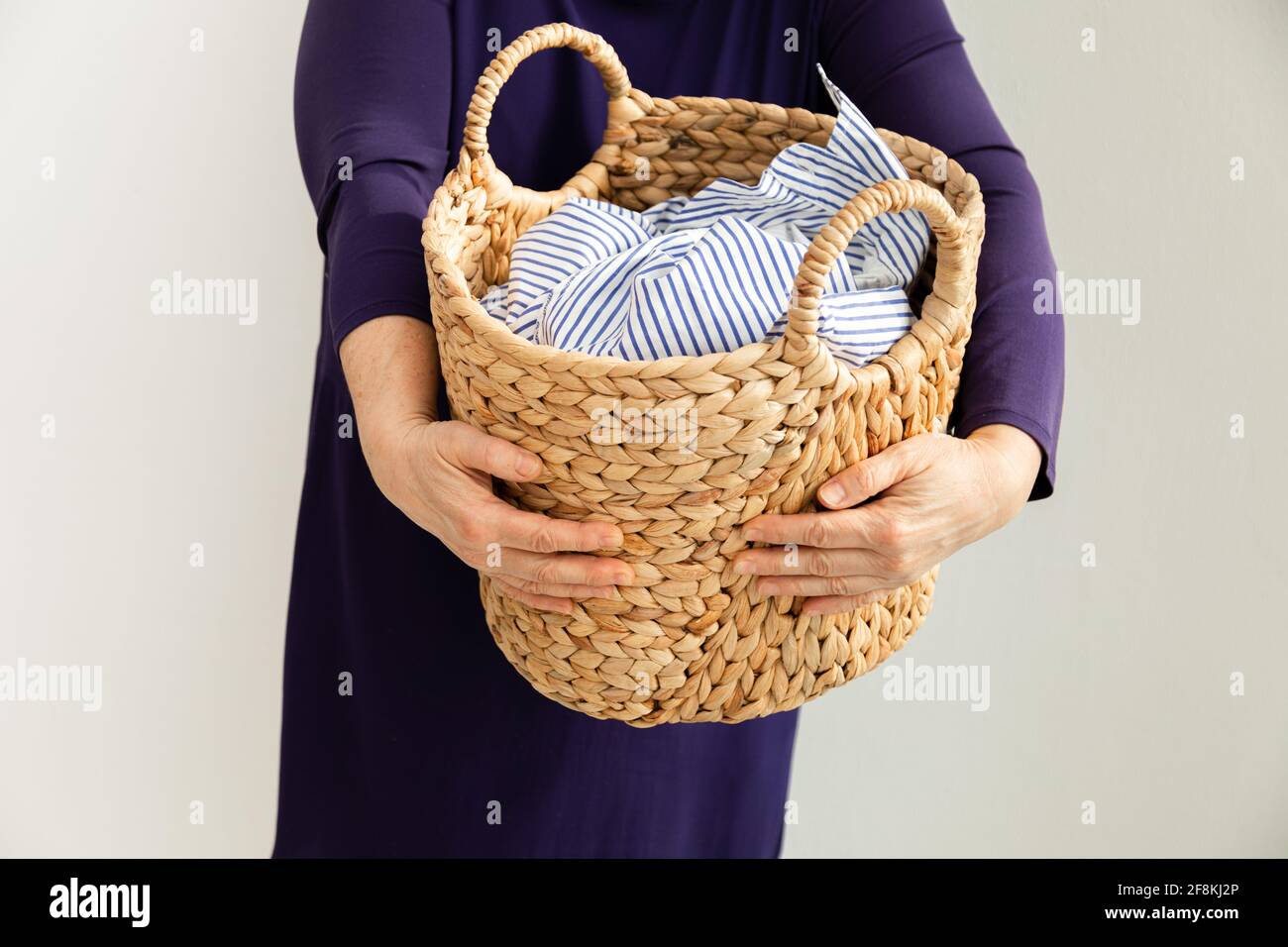 donna che tiene il cesto di vimini con i vestiti sporchi. concetto di pulizia delle faccende domestiche. primo piano foto Foto Stock