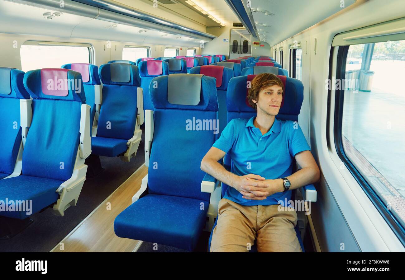 uomo che viaggia in treno e guarda fuori da una finestra. viaggiatore in viaggio. Foto Stock