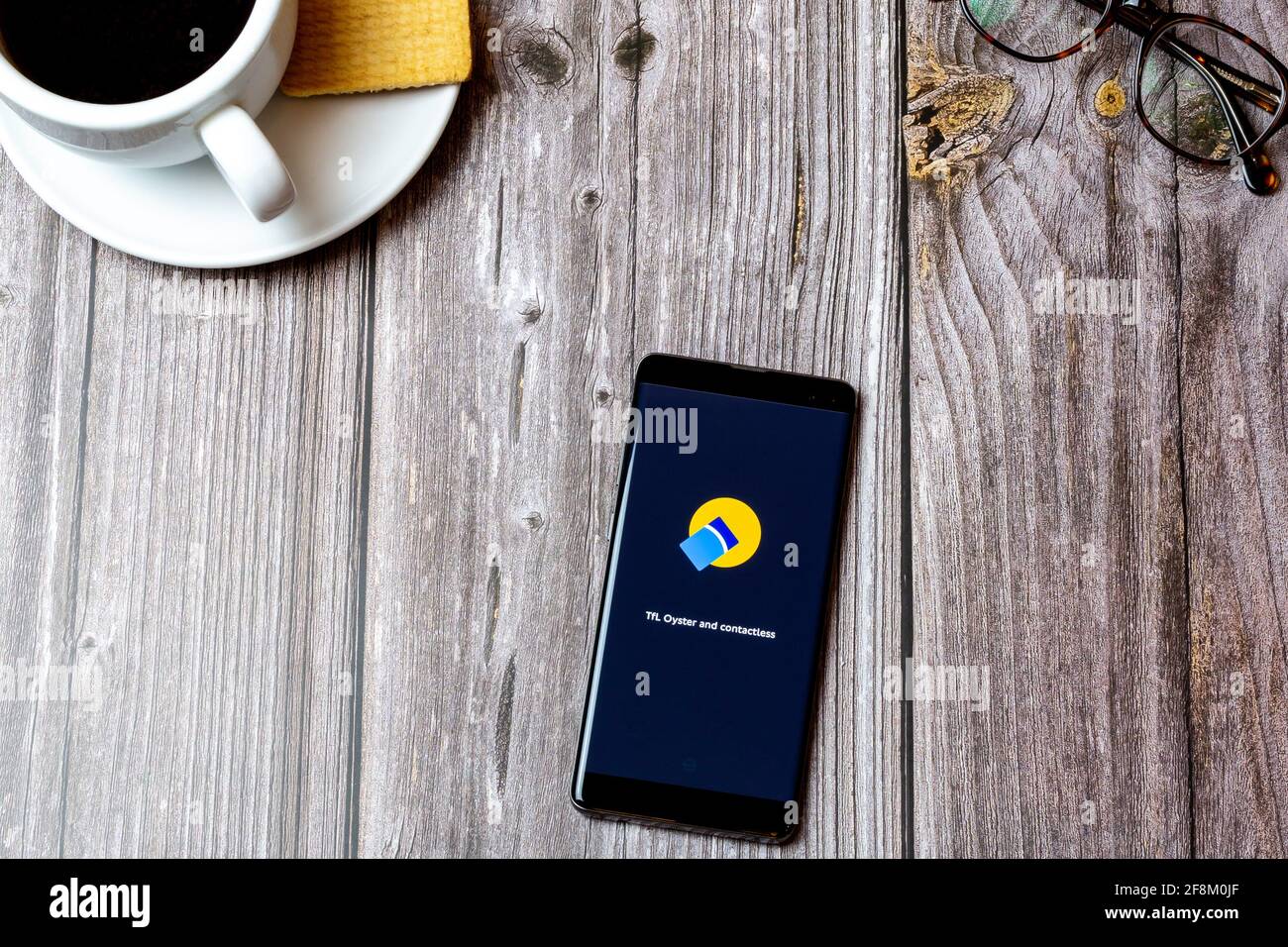 Un telefono cellulare o un telefono cellulare posato su un legno Tabella che mostra l'applicazione della scheda Oyster sullo schermo Foto Stock