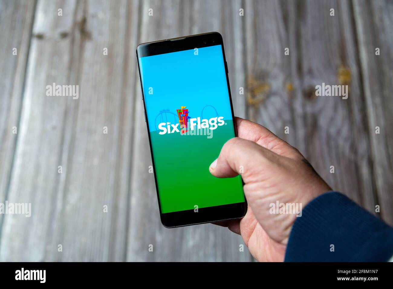 Un telefono cellulare o un telefono cellulare in attesa in un Mano che mostra l'app Six Flags sullo schermo Foto Stock