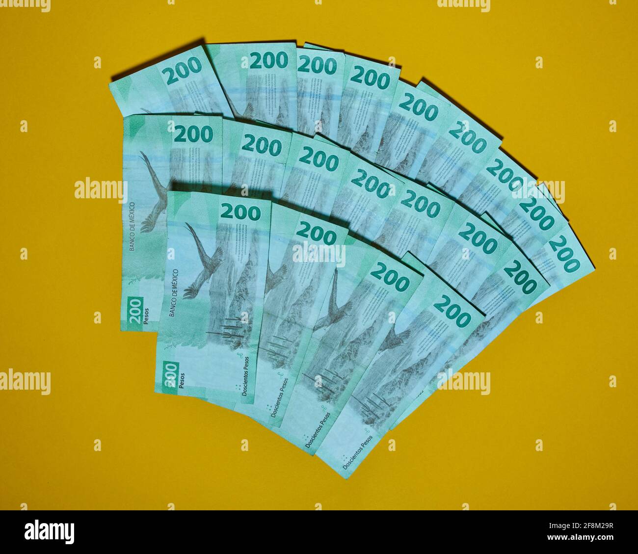 Vista dall'alto di due centinaia di pesos messicani isolati sfondo giallo Foto Stock