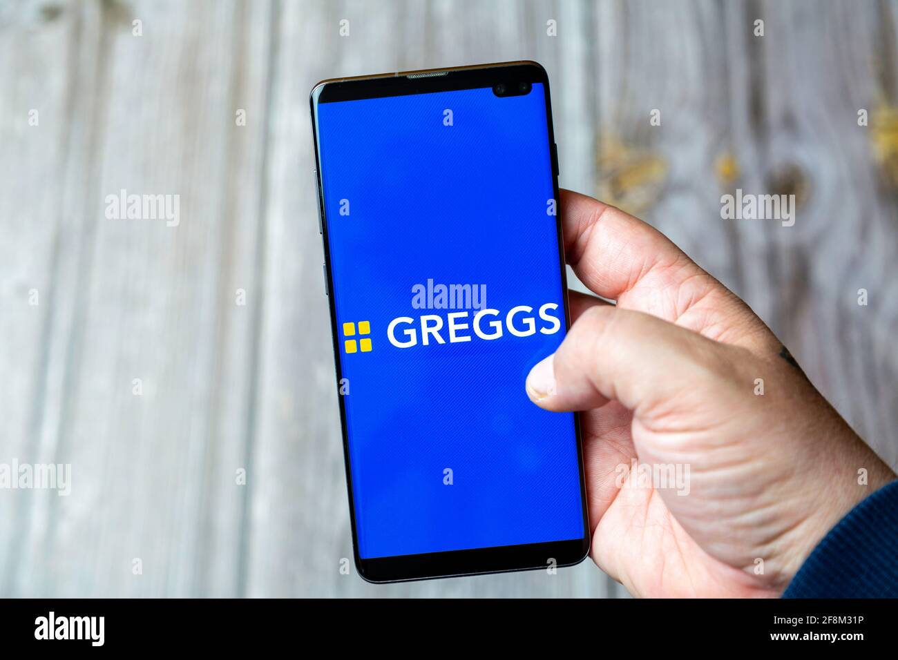 Un telefono cellulare o un telefono cellulare in attesa in un Mano che mostra l'applicazione Greggs sullo schermo Foto Stock