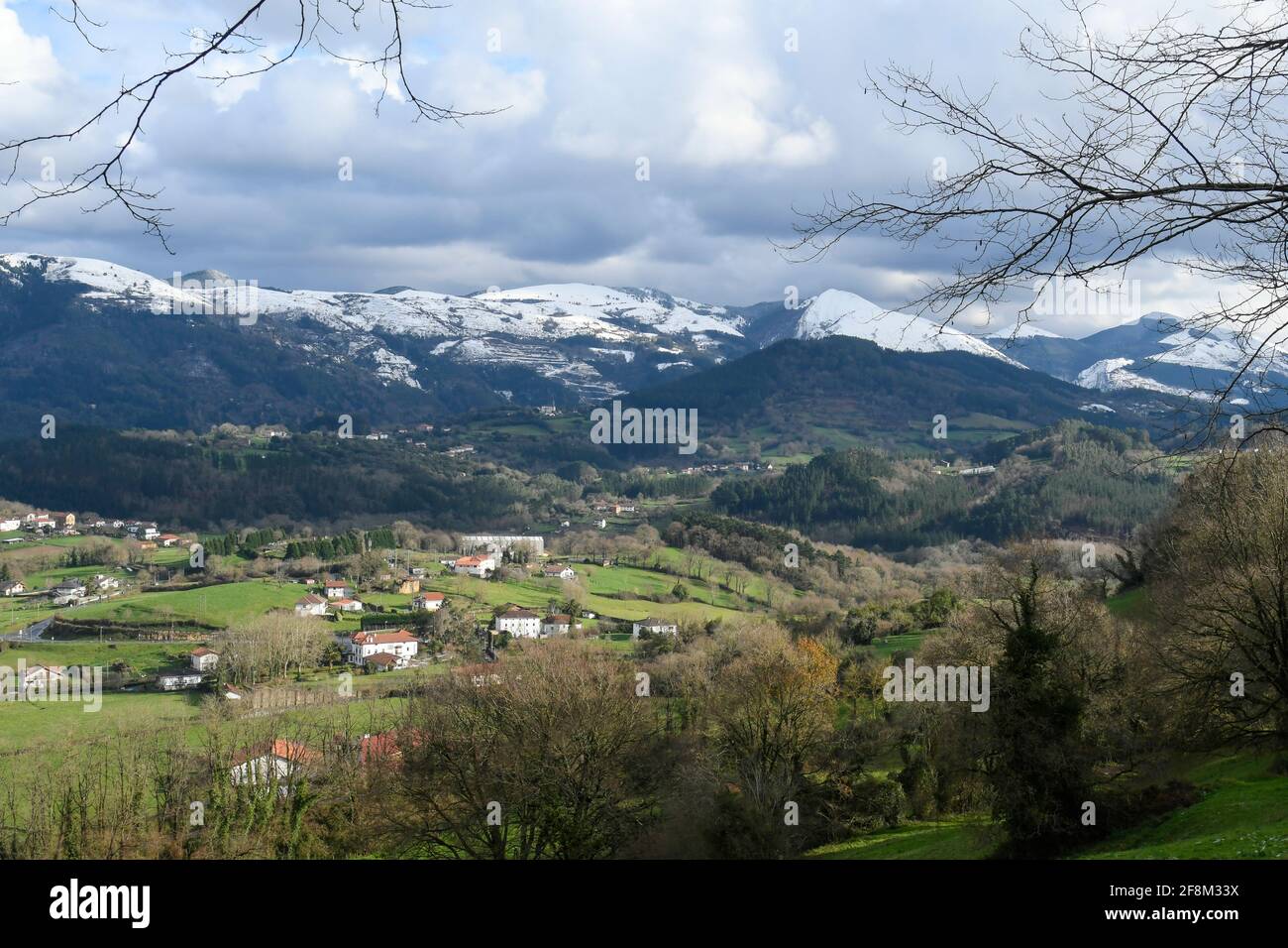 Valle tipica dei Paesi Baschi con le montagne innevate sullo sfondo Foto Stock