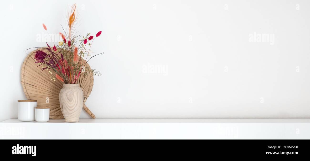 Intestazione di bouquet di fiori secchi colorati in stile boho vaso di legno in piedi su un ripiano bianco con un sacco di spazio di copia Foto Stock