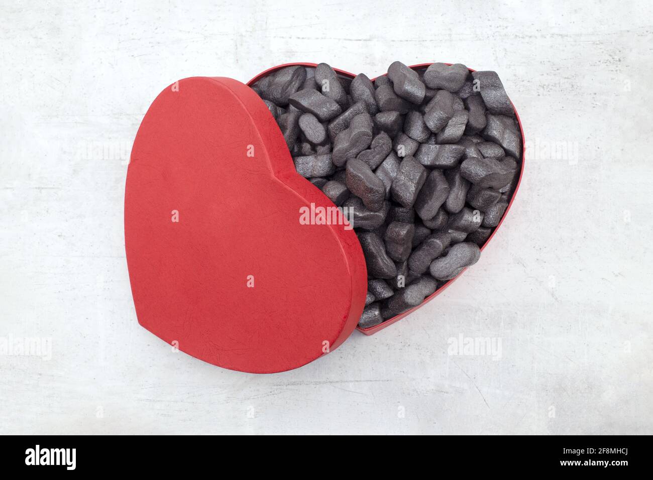 Cardbox a forma di cuore con noccioline nere granulato protettivo Styrofoam chips concetto di giorno di amore o di San Valentino Foto Stock