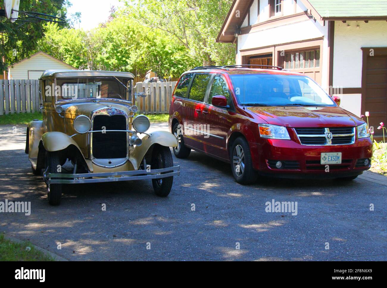 Un furgone rosso e modello A in piedi su un vialetto in asfalto , vicino ad un doppio garage in una giornata di sole. Foto Stock