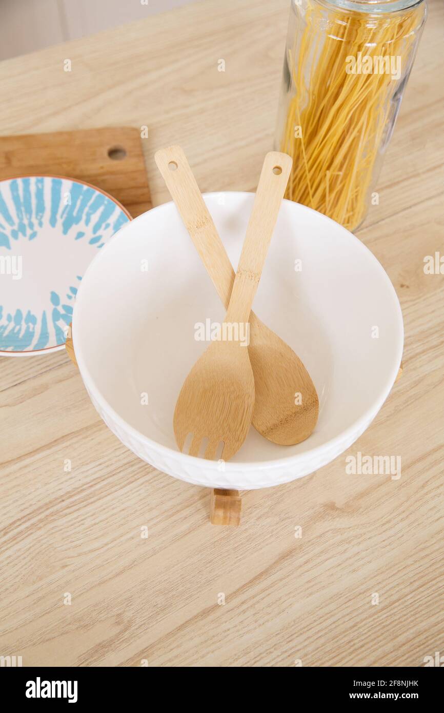 Piastra in ceramica bianca profonda con cucchiaio in legno e forchetta cucina scandinava leggera al mattino Foto Stock