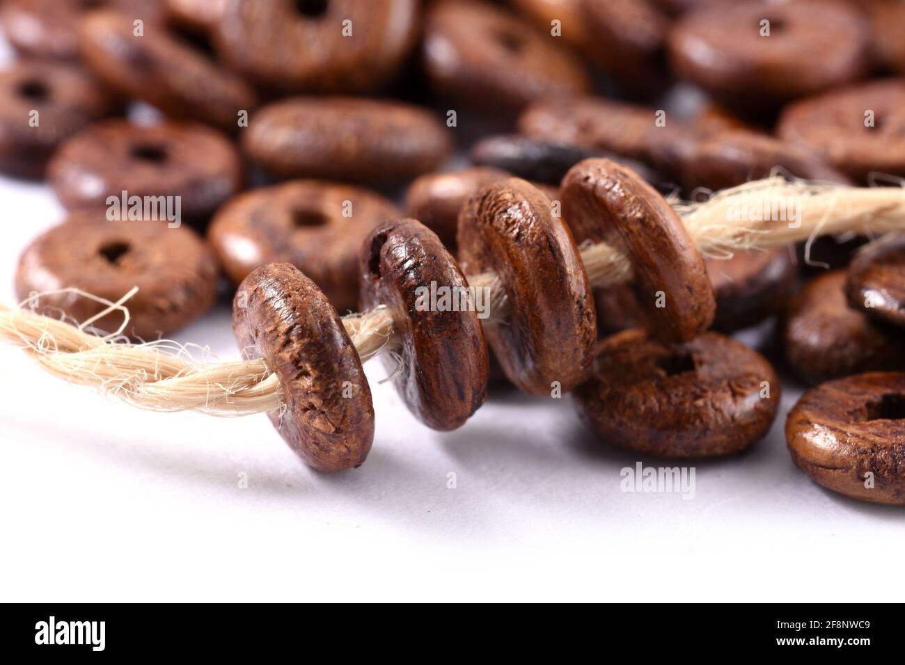 Perline di legno con corda di iuta naturale corda di spago su sfondo bianco primo piano, macro Foto Stock