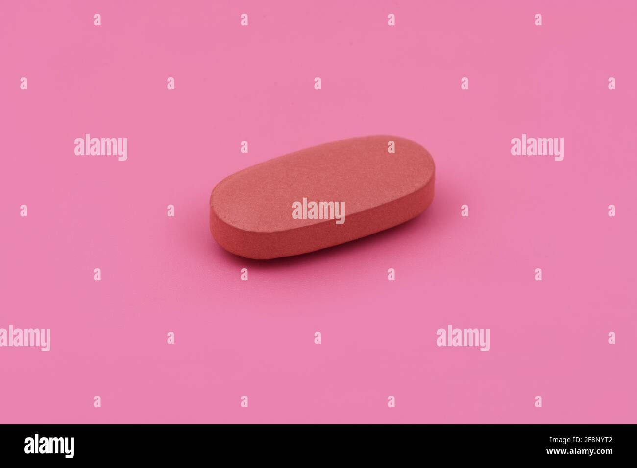 Compressa di medicina farmaceutica di forma ovale su sfondo rosa, spazio di copia piatto concetti di medicina bambino rosa di colore sfondo Foto Stock